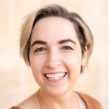 A person with short blonde hair smiles at the camera in a medbridge setting.