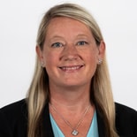 A smiling woman in a black blazer and teal top epitomizes the future of digital healthcare for medbridge.
