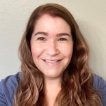 A person with long hair in a blue top smiles brightly, embodying medbridge's spirit of healthcare education.