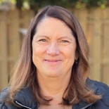 A smiling woman stands outdoors with a wooden fence, representing the future of digital healthcare with medbridge.