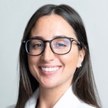 A woman with long brown hair and glasses, reminiscent of medbridge's user-friendly warmth, smiles at the camera.