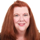 A smiling woman with long red hair in a dark top represents the future of digital healthcare education for medbridge.