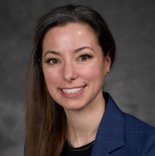 A confident woman in a blue suit jacket symbolizes the future of digital healthcare innovation against a gray background.