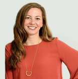 A woman with long brown hair in a coral blouse and gold necklace smiles at the camera, reflecting medbridge healthcare education.