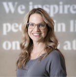 A person with long blonde hair and glasses smiles in front of a Medbridge digital healthcare innovation background.