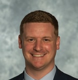 A smiling man in a suit and tie represents the future of digital healthcare for medbridge.