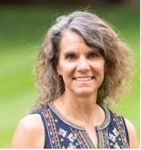 Smiling middle-aged woman with wavy gray hair outdoors, representing digital healthcare innovation at medbridge.