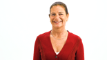 A smiling woman with a ponytail, in a red sweater and necklace, represents the warmth of digital healthcare at medbridge.