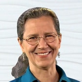 Individual in glasses and blue shirt smiling against a textured white background, promoting medbridge.