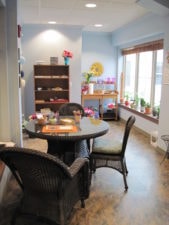 A cozy room with a round table, wicker chairs, and potted plants is ideal for discussing hybrid care strategies.