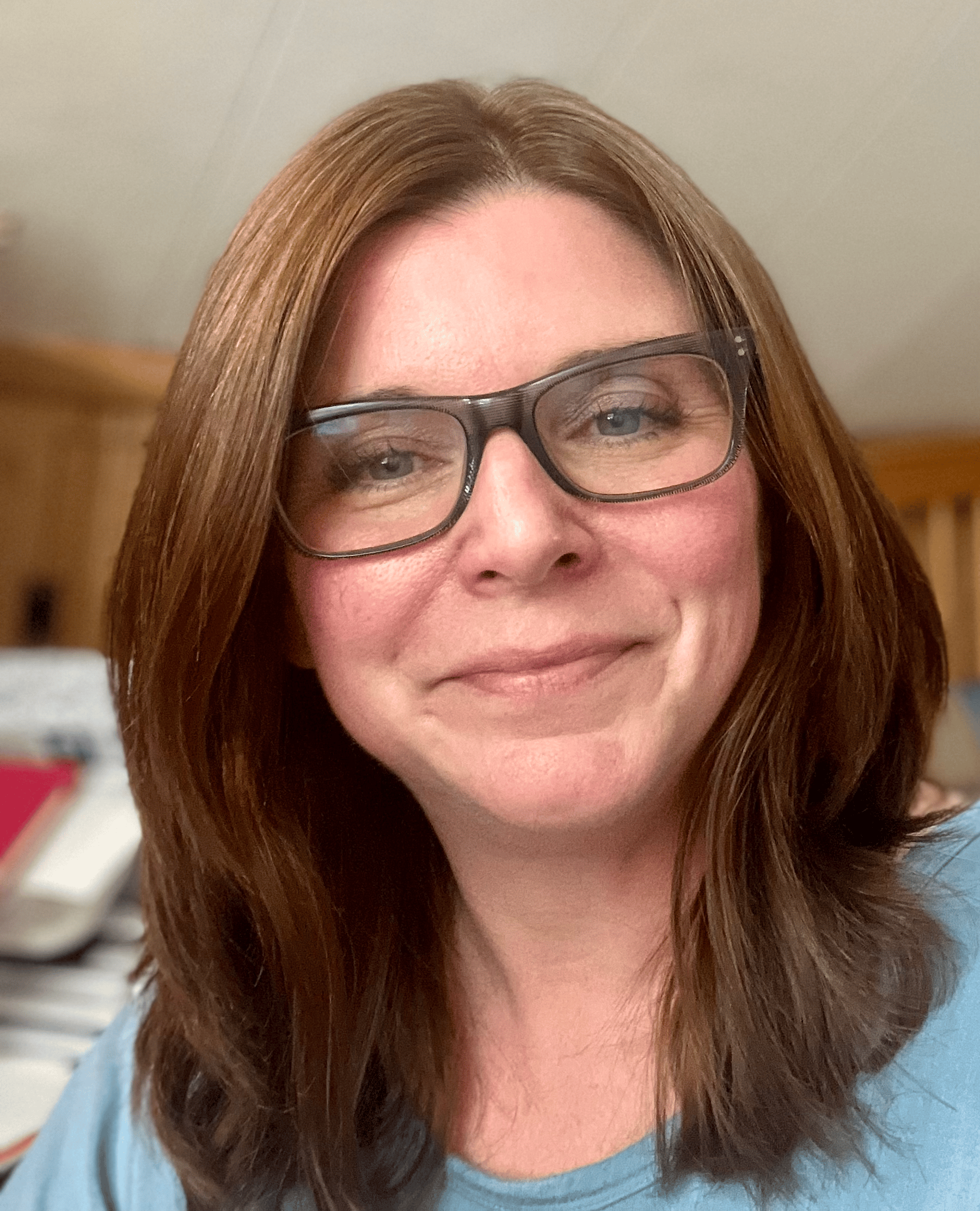 A smiling woman with brown hair and glasses in a light blue top, indoors, representing a positive medbridge healthcare education setting.