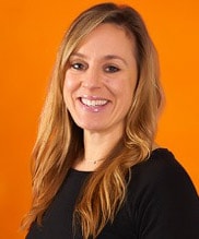 A smiling woman with long blonde hair and a black top symbolizes compassionate healthcare training against an orange background, showing medbridge's essence.