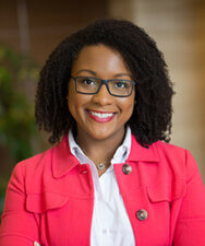 A confident glasses-wearing person in a pink blazer embodies medbridge's enthusiasm for digital healthcare innovation.