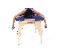 A person on a massage table lifts small weights, demonstrating exercises from medbridge digital healthcare routines.