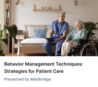 Smiling healthcare worker sits beside an older woman in a wheelchair; medbridge training text appears in the bedroom background.