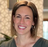 Person with shoulder-length hair and hoop earrings stands smiling in a room with a patterned wall, promoting medbridge.