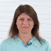 Smiling woman with long brown hair in blue top, representing welcoming patient care software by medbridge.