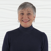 A confident person with short gray hair smiles against a wavy white background, representing Medbridge and their digital healthcare expertise.