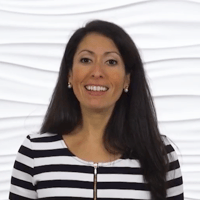 A smiling woman with long dark hair wears a striped top in front of a white background.