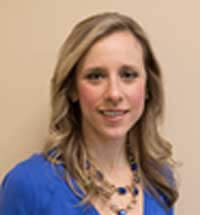 A person with long, wavy hair in a blue top and matching necklace represents hybrid care innovation for medbridge.