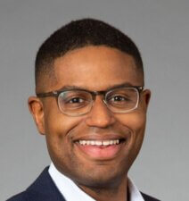 A confident person in a suit, embodying digital healthcare innovation, stands against a neutral background.
