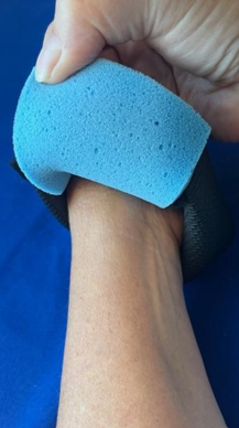 A hand presses a blue foam pad on a forearm against a medbridge blue background.