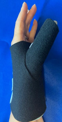 A hand in a black wrist and thumb brace is shown against a blue background.