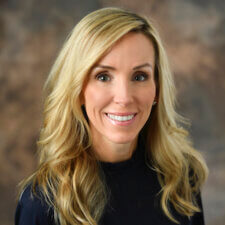 A smiling woman with long blonde hair in a black top represents the ease of digital healthcare, like medbridge, in daily life.