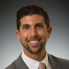 A confident man in a suit and tie, representing expertise at medbridge in patient care software solutions.