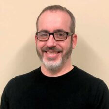 A smiling bearded man with glasses, wearing a black shirt, represents Medbridge's innovative digital healthcare.