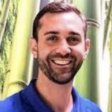 A person in a blue shirt smiles warmly against a bamboo background, embodying compassionate care at medbridge.