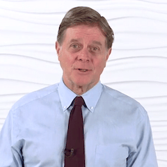 A man in a blue shirt and dark tie stands against a wavy white background, symbolizing digital healthcare's seamless integration with modern environments, as demonstrated by medbridge.
