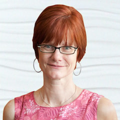 A person with short red hair and glasses in a pink floral top emphasizes healthcare education's impact, related to medbridge.