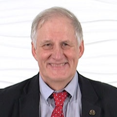 A smiling person with short white hair, in a suit and red polka dot tie, represents Medbridge's innovative digital healthcare spirit.