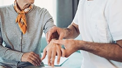 Clinician examining a patient's wrist and hand during a carpal tunnel syndrome assessment.