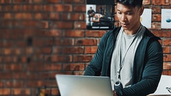A person uses a laptop in a brick-walled room with medbridge posters.
