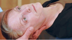 A person lying down receives a chiropractic neck adjustment with emphasis on the practitioner's hand positioning.