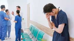 A nurse in scrubs appears distressed while medbridge professionals converse nearby.