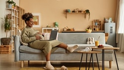Pregnant woman using a laptop in her living room to explore medbridge digital healthcare resources.