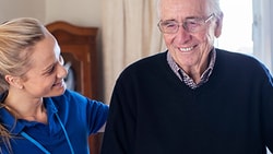 Home health provider supporting an older adult during a visit, representing CMS 2023 home health final payment rule updates.