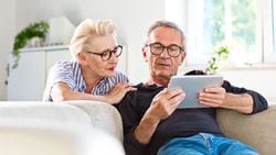 Older couple using a tablet together at home, illustrating engagement with technology among the "silver tsunami" generation.