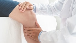 Orthopedic clinician examines a patient's knee during a joint replacement recovery assessment