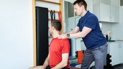 Physical therapist evaluating cervical mobility in a patient during concussion management in a clinical rehab setting.