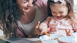 Woman and child dining happily at a table with a nearby laptop showing medbridge.