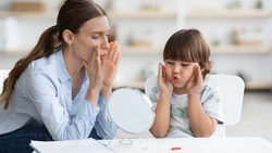 Speech therapist demonstrating dynamic temporal and tactile cueing (DTTC) techniques with child during speech therapy session.