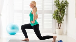 Woman lunging in a bright room with a yoga ball and plant; medbridge branding.