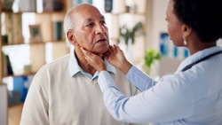 Clinician palpates patient’s neck during swallow exam, assessing for signs of esophageal dysphagia.