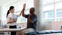 Physical therapist assisting a patient with arm mobility during evaluation for upper extremity osteoarthritis.