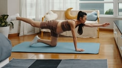 Woman performing bird-dog exercise during pregnancy on a yoga mat at home as part of a safe prenatal fitness routine.