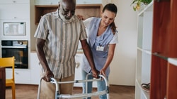 female clinician helping senior male walking - functional independence measure